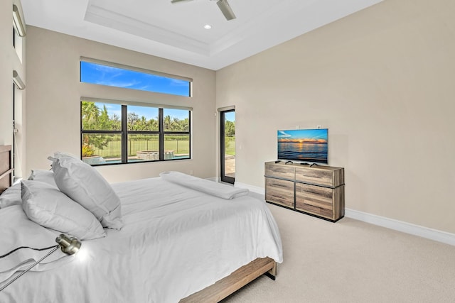 bedroom featuring baseboards, a raised ceiling, a ceiling fan, carpet, and a high ceiling