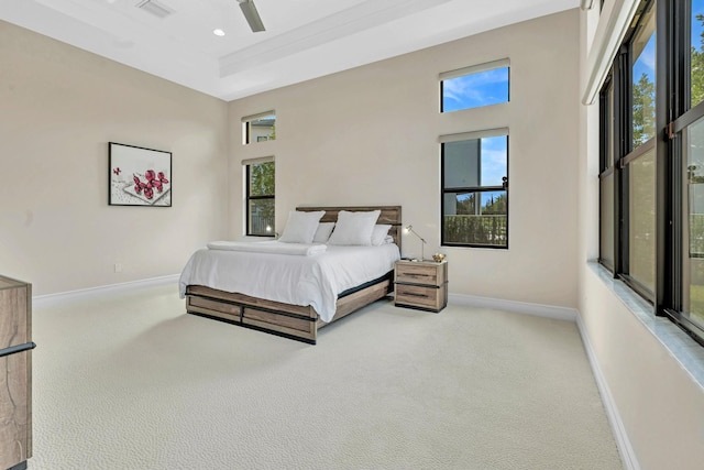 carpeted bedroom featuring a raised ceiling, a high ceiling, and ceiling fan