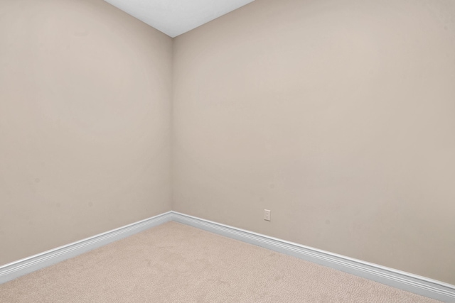 carpeted empty room featuring baseboards