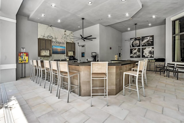 kitchen featuring dark countertops, ceiling fan, a peninsula, and a kitchen breakfast bar