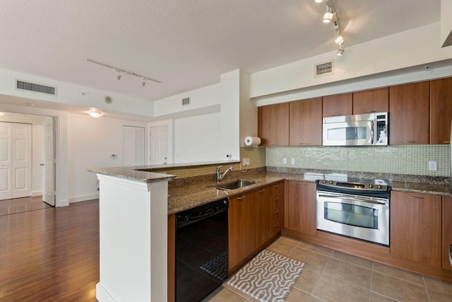 kitchen with sink, dishwasher, kitchen peninsula, dark stone countertops, and range