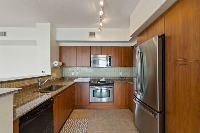 kitchen featuring decorative backsplash, appliances with stainless steel finishes, light stone counters, sink, and light tile patterned floors