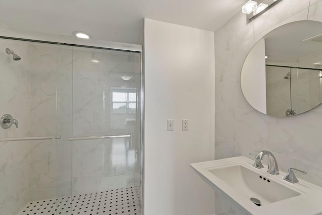 bathroom with a shower with door, tile walls, and sink