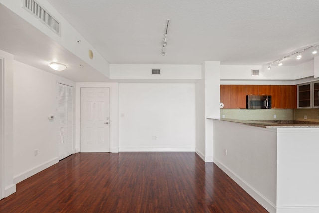 unfurnished living room featuring dark hardwood / wood-style flooring and rail lighting