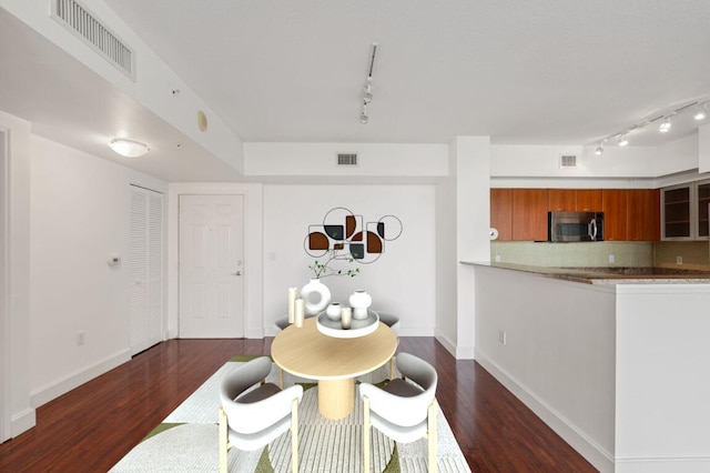 dining area featuring dark wood-type flooring and track lighting