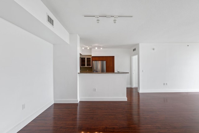 unfurnished living room featuring track lighting and dark hardwood / wood-style floors