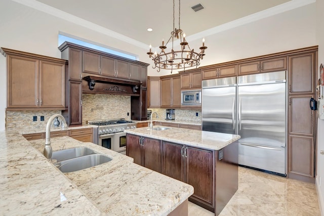 kitchen featuring pendant lighting, stainless steel appliances, a kitchen island with sink, and sink