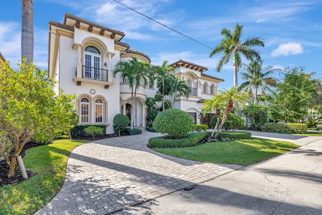 mediterranean / spanish-style home with a balcony, a front lawn, and a garage