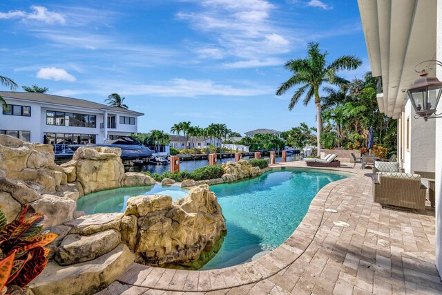 view of pool with an in ground hot tub, a water view, and a patio area