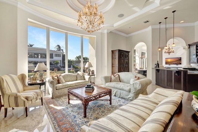 living room with a towering ceiling, a raised ceiling, ornamental molding, and a notable chandelier