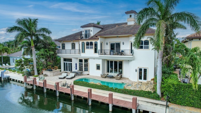 rear view of house with french doors, a patio, a balcony, and a water view