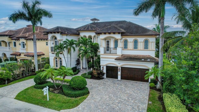 mediterranean / spanish-style home with a front lawn, a garage, a balcony, and french doors