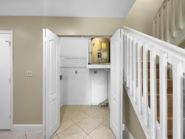 laundry room featuring electric dryer hookup, electric water heater, and light tile patterned floors