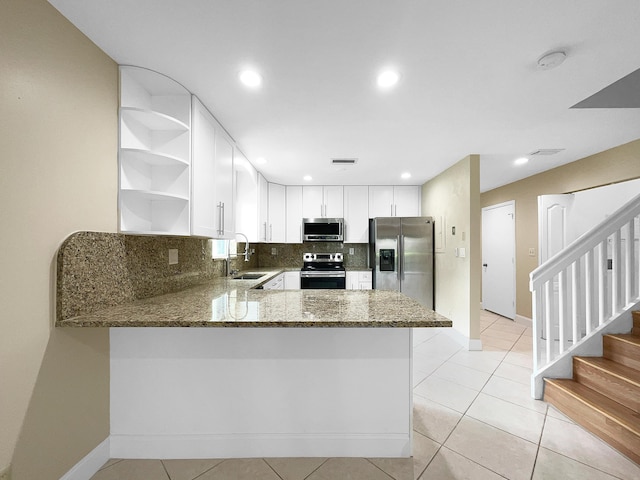 kitchen featuring kitchen peninsula, appliances with stainless steel finishes, stone countertops, and sink