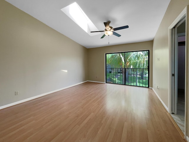 empty room with a skylight, ceiling fan, and light hardwood / wood-style flooring