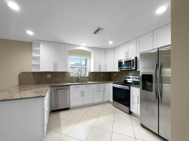 kitchen featuring appliances with stainless steel finishes, tasteful backsplash, sink, light tile patterned floors, and white cabinetry