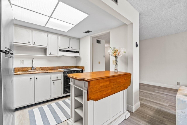 kitchen with sink, range with electric cooktop, light hardwood / wood-style flooring, a textured ceiling, and white cabinetry