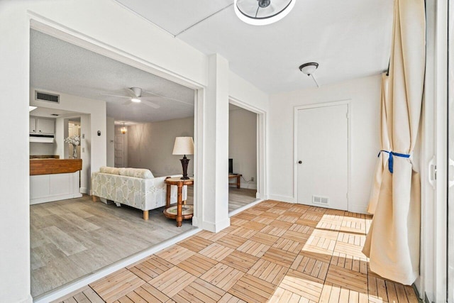 foyer entrance featuring ceiling fan, a textured ceiling, and light parquet floors