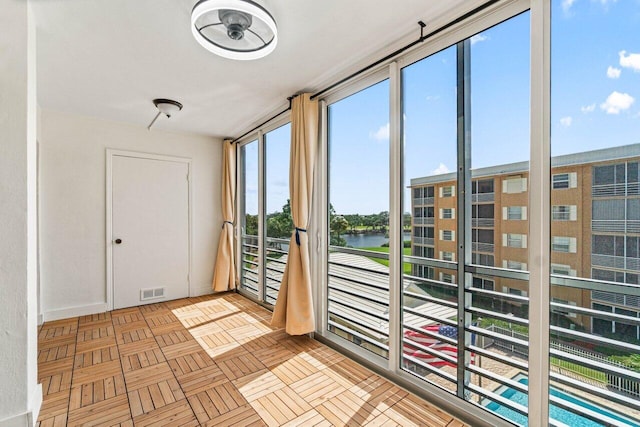 doorway featuring light parquet flooring, a water view, and a healthy amount of sunlight