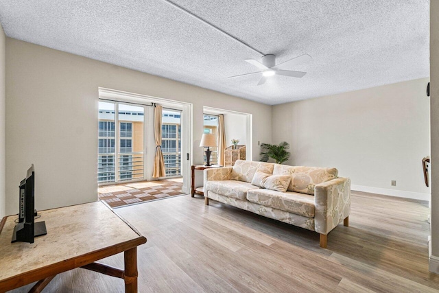 living room with light wood-type flooring, a textured ceiling, and ceiling fan