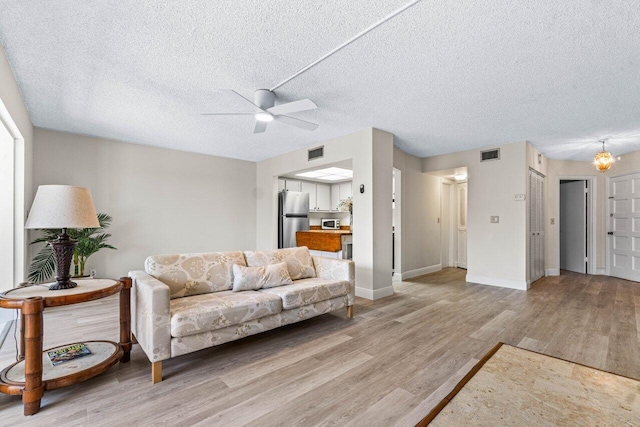 living room featuring a textured ceiling, light wood-type flooring, and ceiling fan