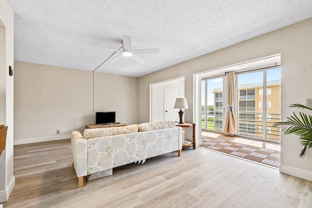 living room with a textured ceiling, light hardwood / wood-style flooring, and ceiling fan