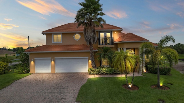 mediterranean / spanish-style home featuring a lawn, a balcony, and a garage