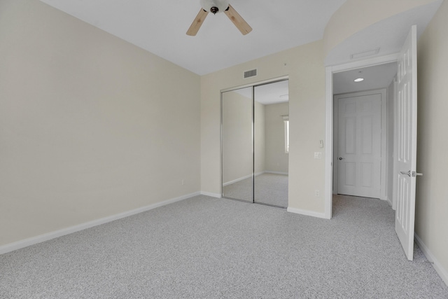 unfurnished bedroom with light carpet, a closet, and ceiling fan