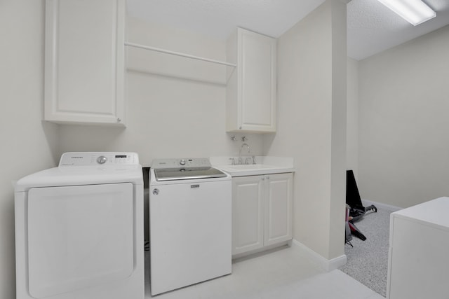 laundry area featuring a sink, washing machine and dryer, baseboards, cabinet space, and a textured ceiling