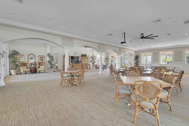 carpeted dining space featuring decorative columns, crown molding, and ceiling fan