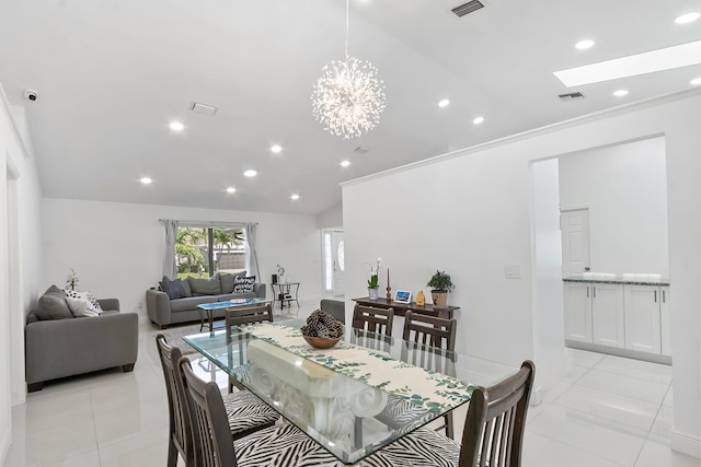 tiled dining area with ornamental molding, lofted ceiling with skylight, and a notable chandelier