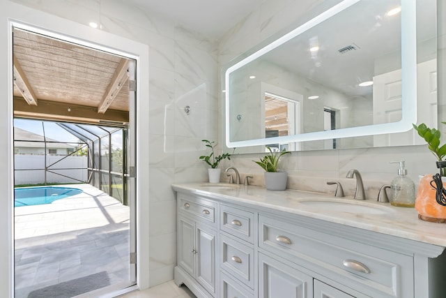 bathroom featuring beam ceiling, vanity, and tile walls