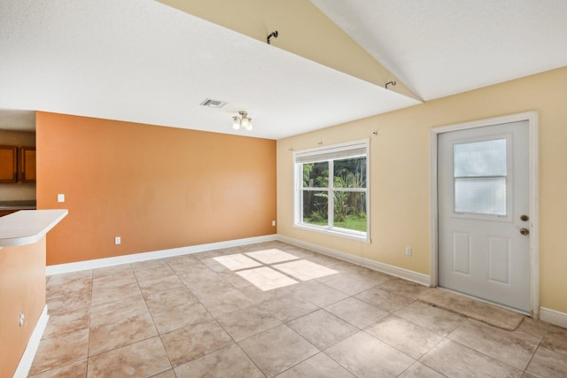 interior space with light tile flooring and vaulted ceiling