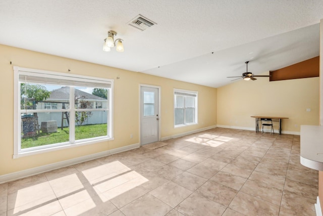 unfurnished living room featuring a healthy amount of sunlight, lofted ceiling, and light tile floors