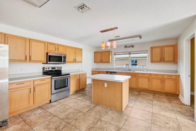 kitchen featuring a center island, a textured ceiling, stainless steel appliances, decorative light fixtures, and light tile floors