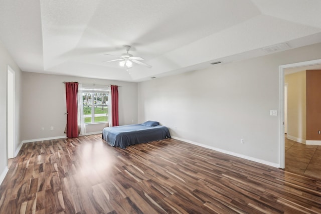 unfurnished bedroom with a tray ceiling, ceiling fan, and dark tile floors