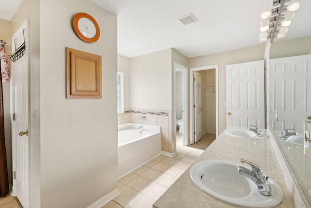 bathroom featuring double vanity, toilet, tile floors, and a bathing tub