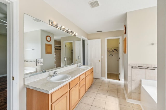 bathroom with tile floors, a bathing tub, and double sink vanity