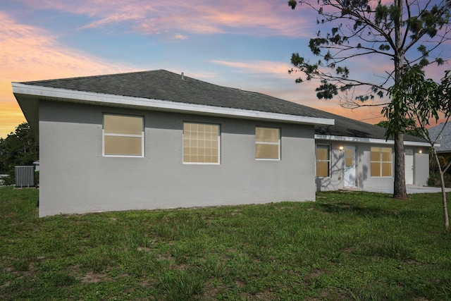 property exterior at dusk featuring a lawn