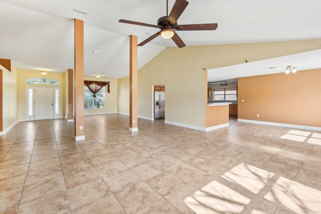 unfurnished living room with high vaulted ceiling, ceiling fan, and light tile floors