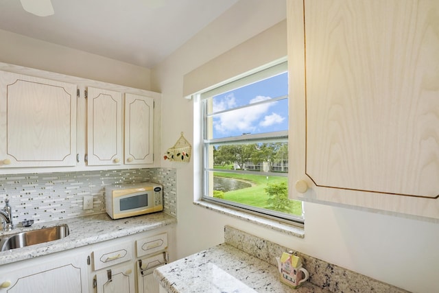 kitchen featuring light stone countertops, backsplash, and sink