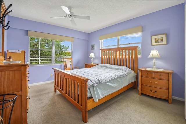 bedroom featuring ceiling fan, light carpet, and a textured ceiling