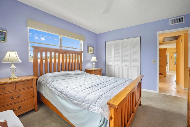 carpeted bedroom with ceiling fan, a textured ceiling, and a closet