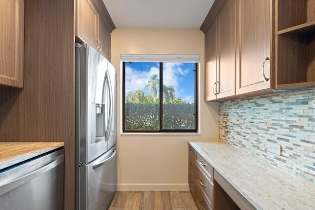 kitchen featuring appliances with stainless steel finishes, light hardwood / wood-style floors, and tasteful backsplash