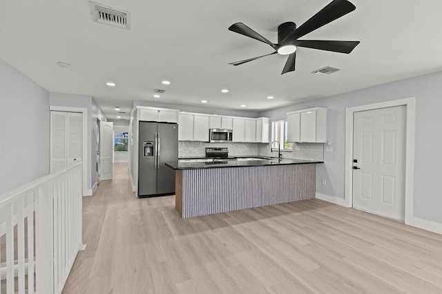 kitchen with appliances with stainless steel finishes, white cabinetry, ceiling fan, and light hardwood / wood-style flooring