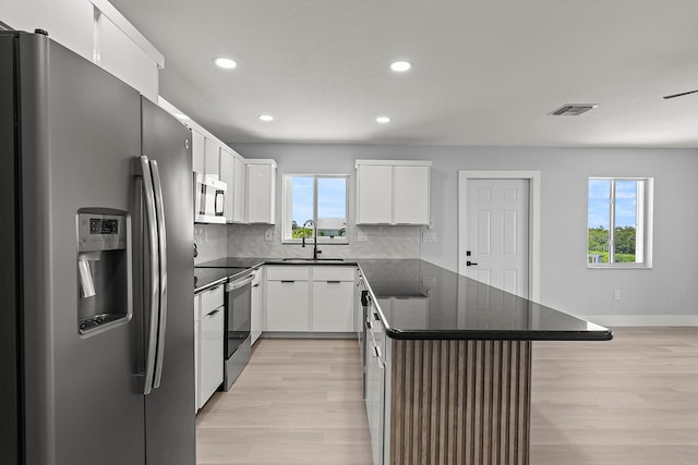 kitchen featuring stainless steel appliances, tasteful backsplash, light wood-type flooring, and a healthy amount of sunlight