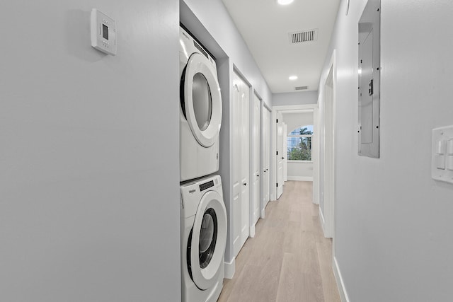 laundry area with stacked washing maching and dryer and light hardwood / wood-style floors