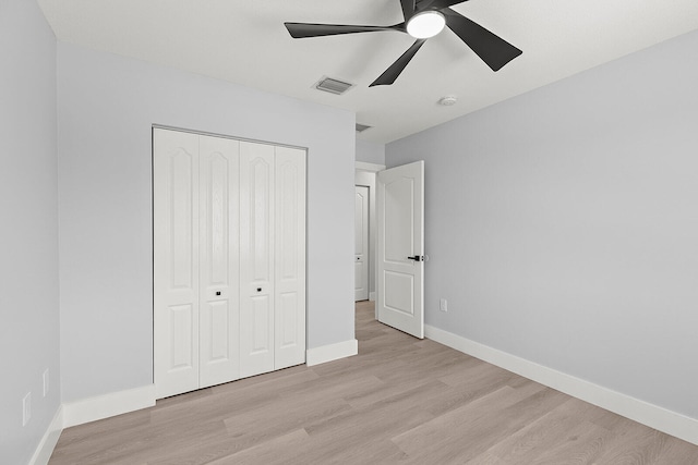 unfurnished bedroom featuring ceiling fan, a closet, and light wood-type flooring