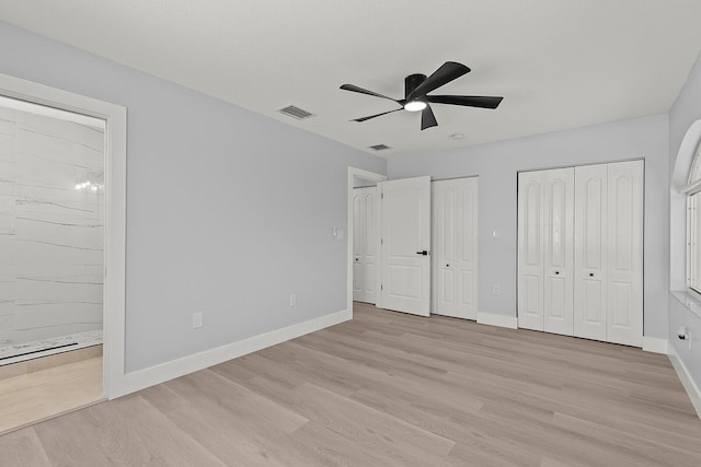 unfurnished bedroom featuring two closets, light wood-type flooring, and ceiling fan