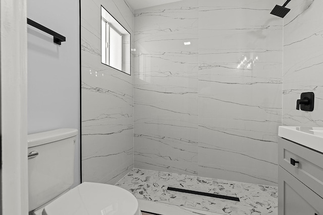 bathroom with tiled shower, vanity, and toilet